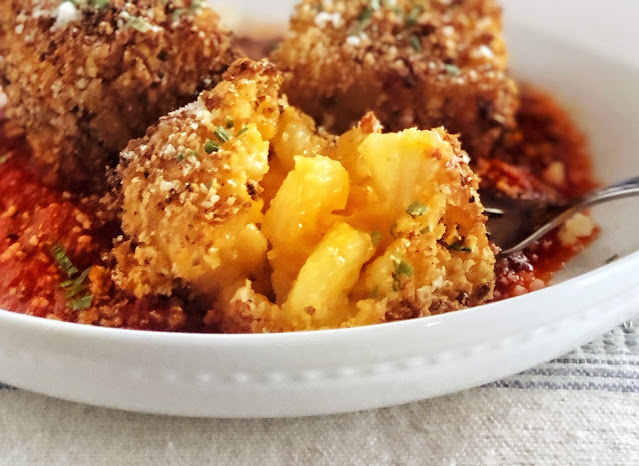 fried mac and cheese bites in tomato sauce in a white bowl