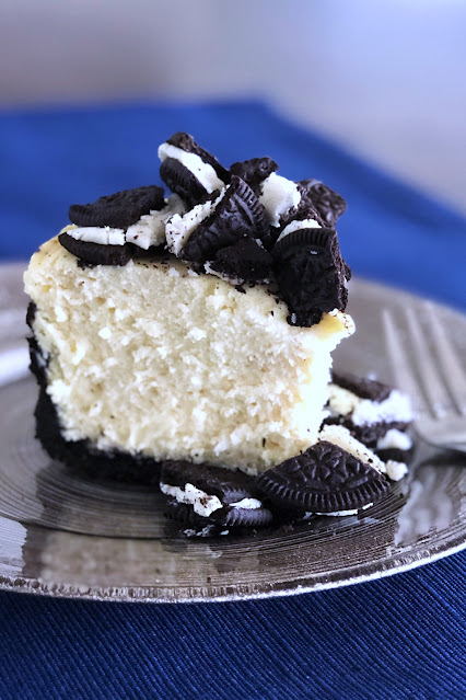 a slice of cheesecake covered in oreos on a grey plate