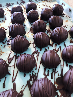 chocolate covered peanut butter balls with chocolate drizzle on a baking pan