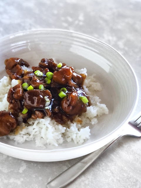 teriyaki chicken over white rice on a white plate