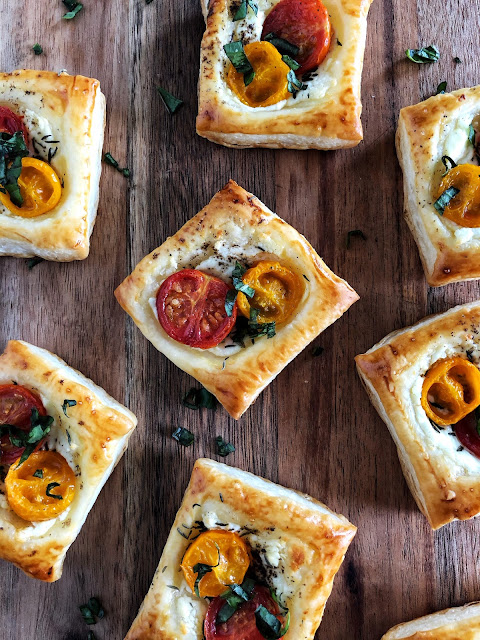 puff pastry with goat cheese, roasted tomatoes and herbs on a wooden background