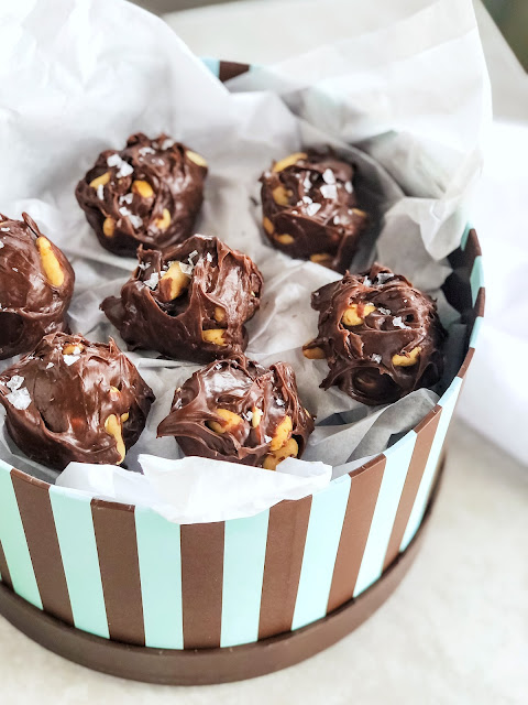 chocolate peanut clusters sprinkled with salt and boxed in white tissue paper
