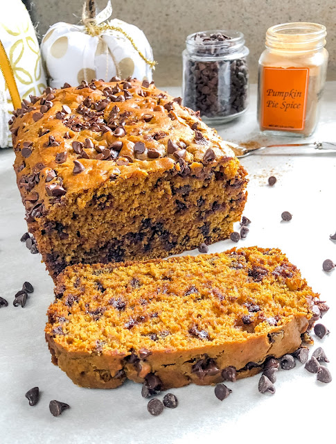 a sliced loaf of chocolate chip pumpkin spice bread surrounded with chocolate chips