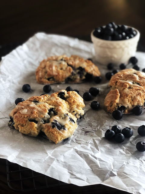 blueberry scones on parchment paper with blueberries on the side