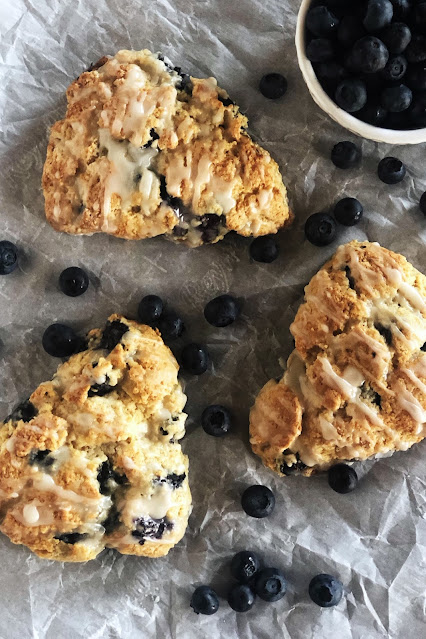 blueberry scones on parchment paper with blueberries on the side