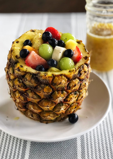 a pineapple filled with fruit drizzled with dressing