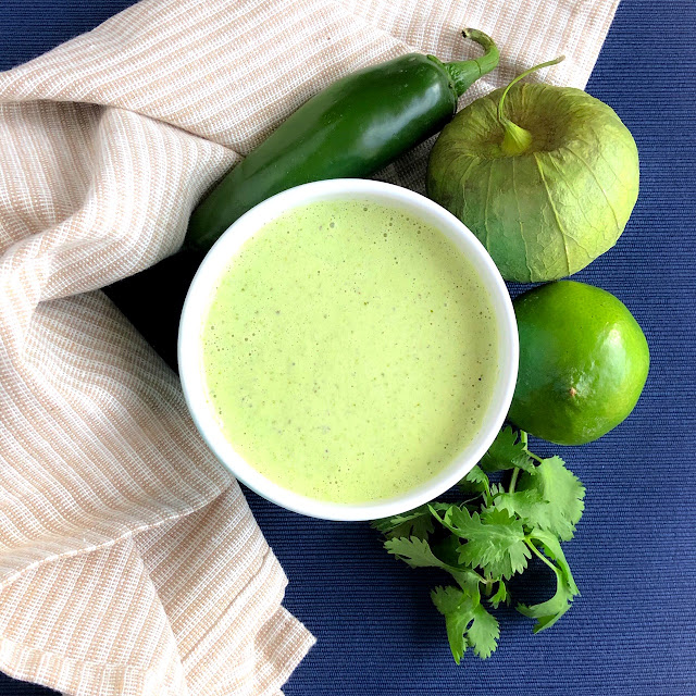 creamy green dressing in a white bowl with tomatillo, jalapeno, lime and cilantro