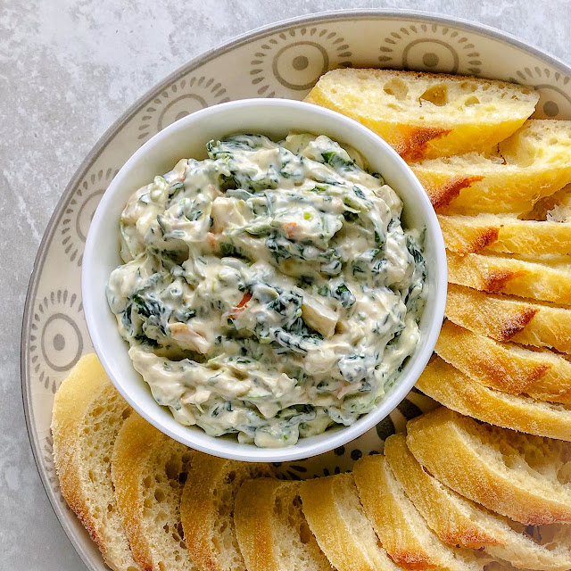spinach dip in a white bowl with bread