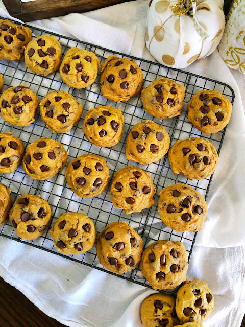 pumpkin chocolate chip cookies on a cooling rack placed on a white cloth