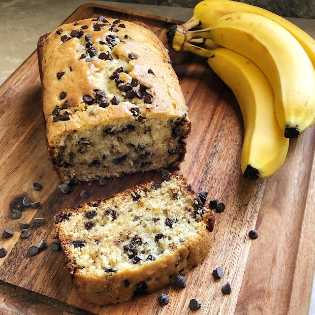 chocolate chip banana bread on a cutting board with bananas