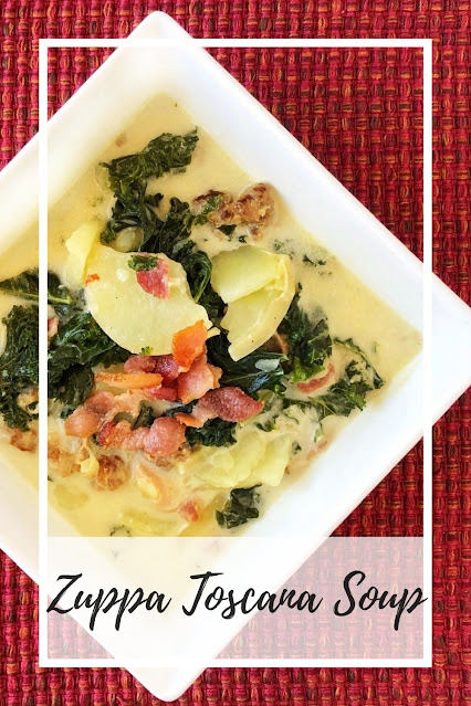 creamy soup with italian sausage, bacon, potatoes and kale in a square white soup bowl on a red mat