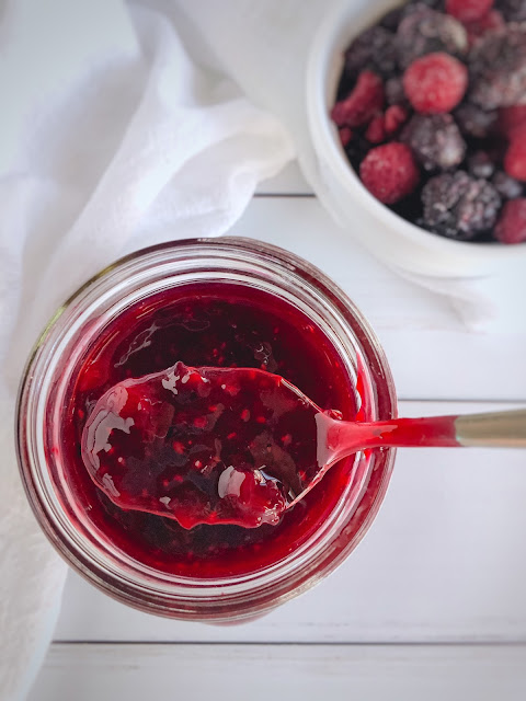 sauce in a mason jar with berries in a white bowl