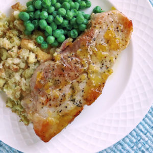 glazed pork with stuffing and peas on a white plate