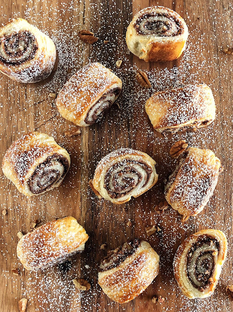Nutella & Pecan Puff Pastry Swirls on a cutting board sprinkled with powdered sugar