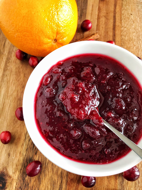 cranberry sauce in a white bowl with an orange and cranberries