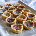 little cups of pastry filled with jam and sprinkled with powdered sugar