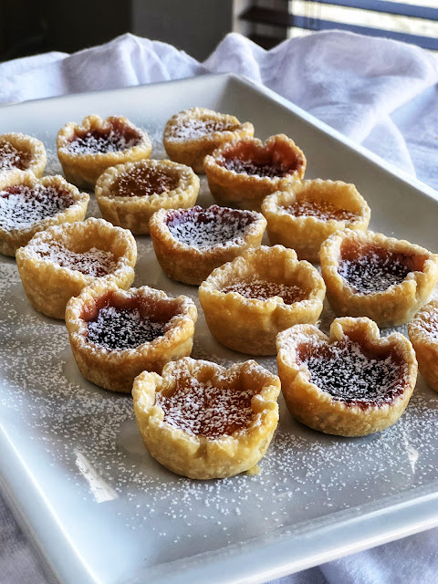 little cups of pastry filled with jam and sprinkled with powdered sugar