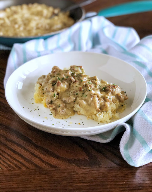biscuits with sausage gravy over the top in a white bowl