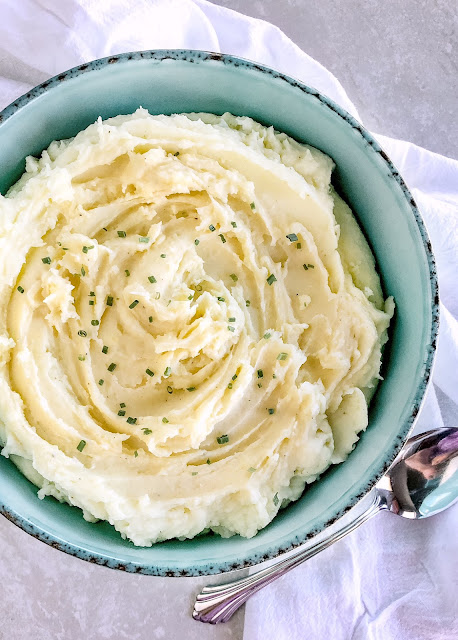 mashed potatoes in teal bowl garnished with chives