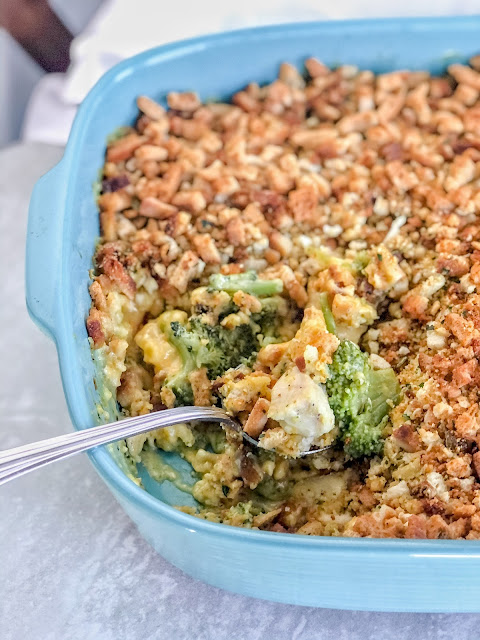 chicken and broccoli casserole in a blue dish with a spoon