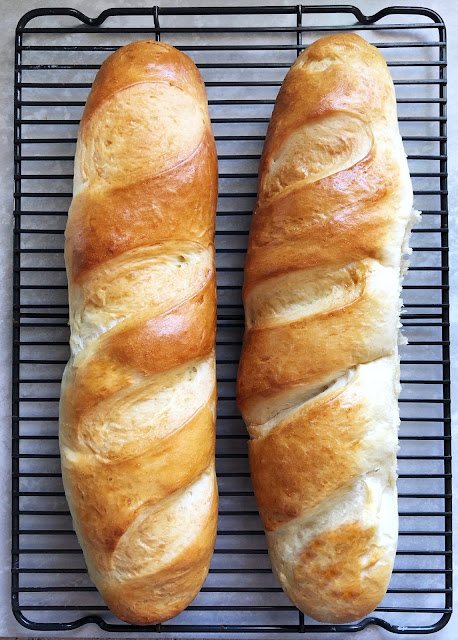 golden brown french baguettes on a cooling rack
