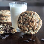 large chocolate chip cookies on the table with a glass of milk