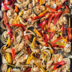chicken peppers and onions on a baking sheet
