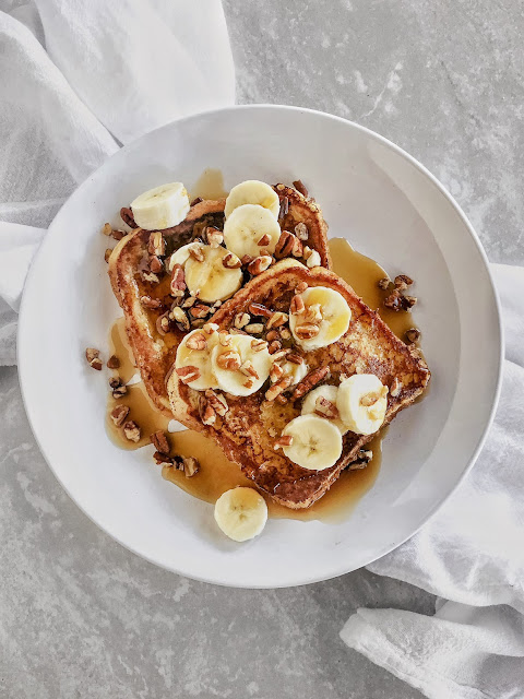 French Toast with pecans, bananas and syrup on a white plate