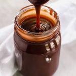 hot fudge sauce dripping off a spoon in to a jar