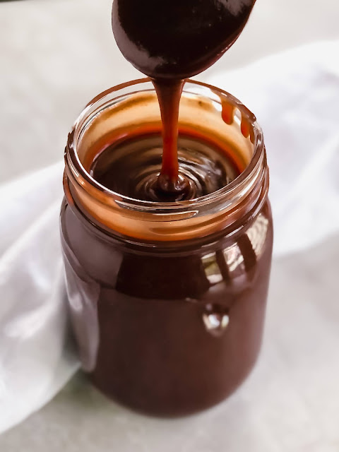 hot fudge sauce dripping off a spoon in to a jar