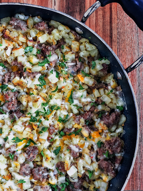 potatoes sausage cheese and parsley in a frying pan
