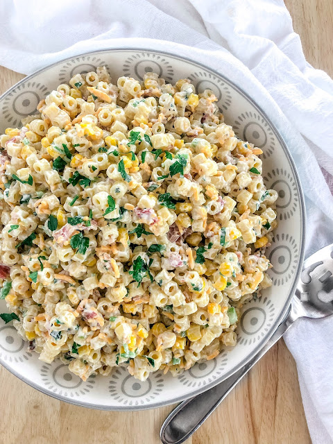 pasta salad with corn bacon cheese and parsley in a white bowl