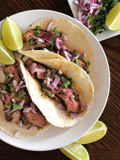 carne asada on tortillas with red onion cilantro and lime