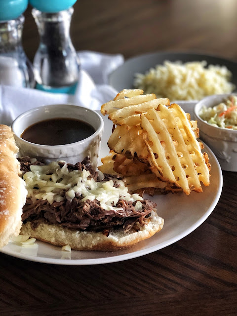 shredded beef on a roll with french fries and dipping sauce