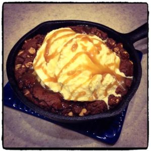 cookie in cast iron pan with ice cream and caramel on top