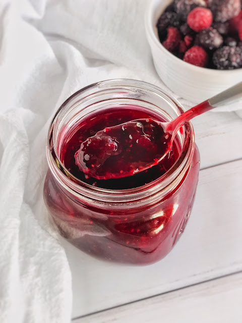 mixed berry sauce in a jar with a spoon