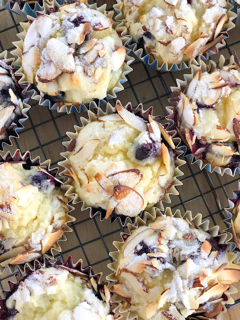 lemon muffins with blueberries and sugared almonds on a cooling rack