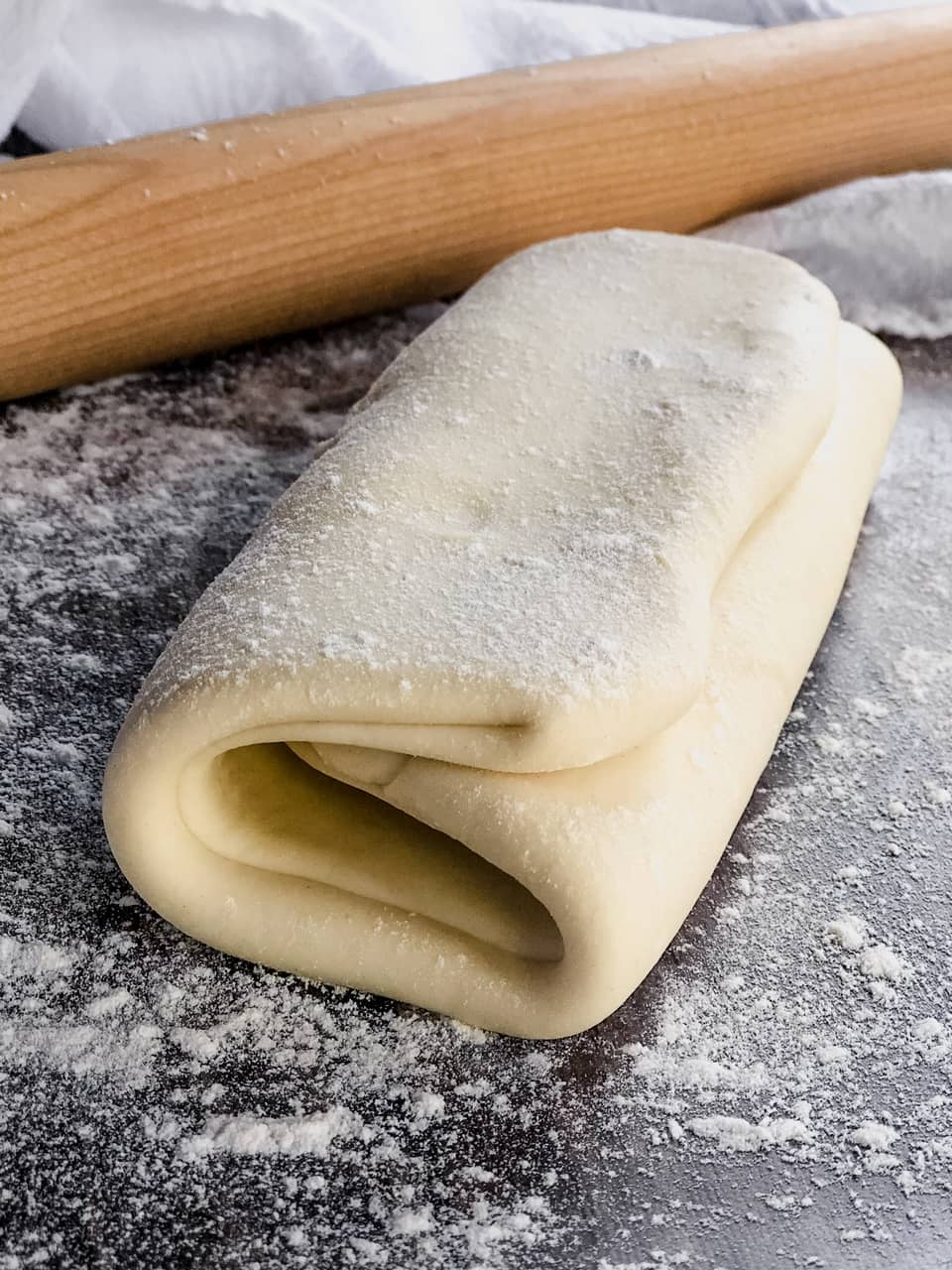 dough on a counter with a rolling pin and cloth