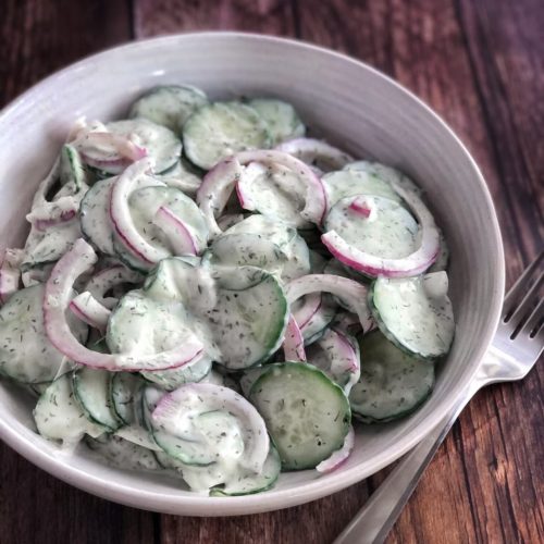 cucumbers and onions with dressing in a bowl