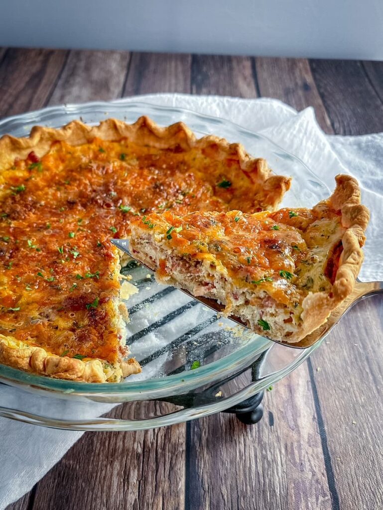 slice of quiche being removed from pie dish