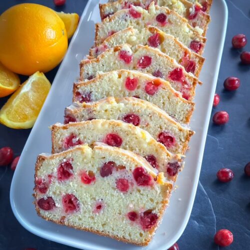 cranberry orange loaf sliced on a white platter