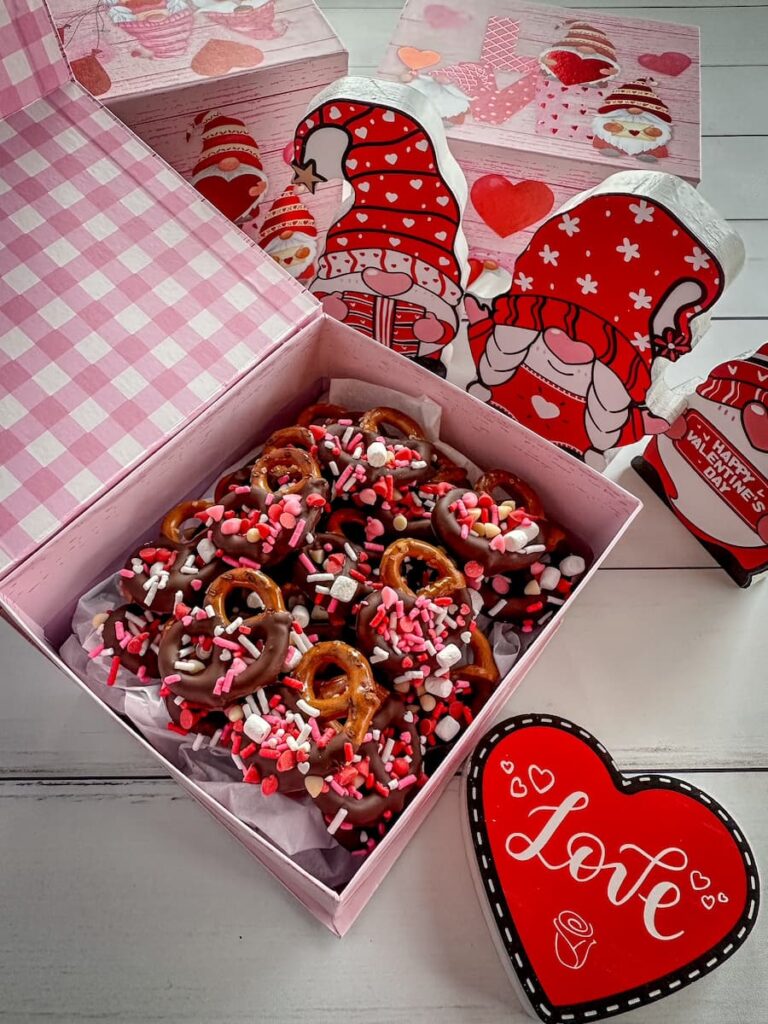 pretzels dipped in chocolate and decorated with sprinkles in a gift box