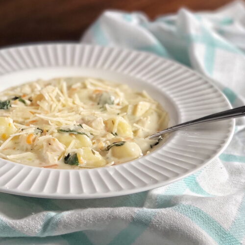 chicken gnocchi soup in a white bowl with a spoon