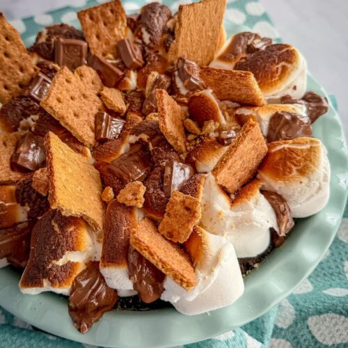 fudgy s’mores brownie bake topped with toasted marshmallows, graham crackers, and melty chocolate in a pie pan.